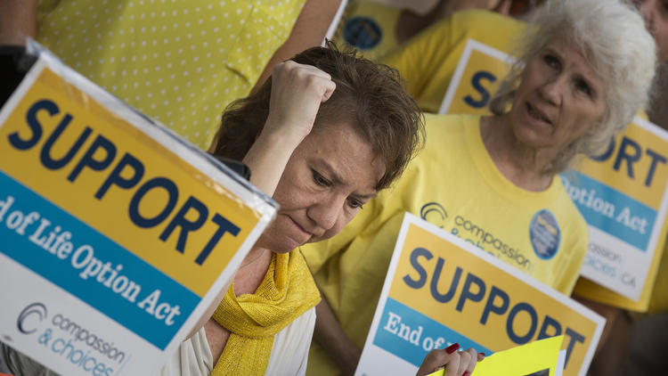 Christy O'Donnell, a terminally ill former LAPD officer, center, thrusts her fist in the air at a rally in support of the End of Life Option Act in Los Angeles. (Credit: Brian van der Brug/Los Angeles Times)