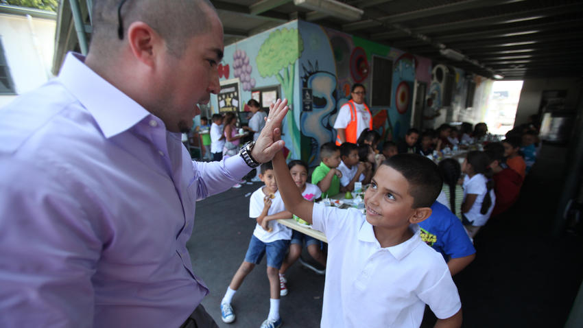 Juan Carlos Rodriguez, left, Title I coordinator, gives a high-five to second-grader Armando Rodriguez, 7, during lunch on the first day of school at Hadden Elementary School in Pacoima in August 2013. (Los Angeles Times)