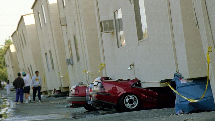 Crushed cars sit underneath a collapsed apartment building in the 19100 block of Victory Boulevard after the 1994 Northridge earthquake. (Credit: Boris Yaro / Los Angeles Times)