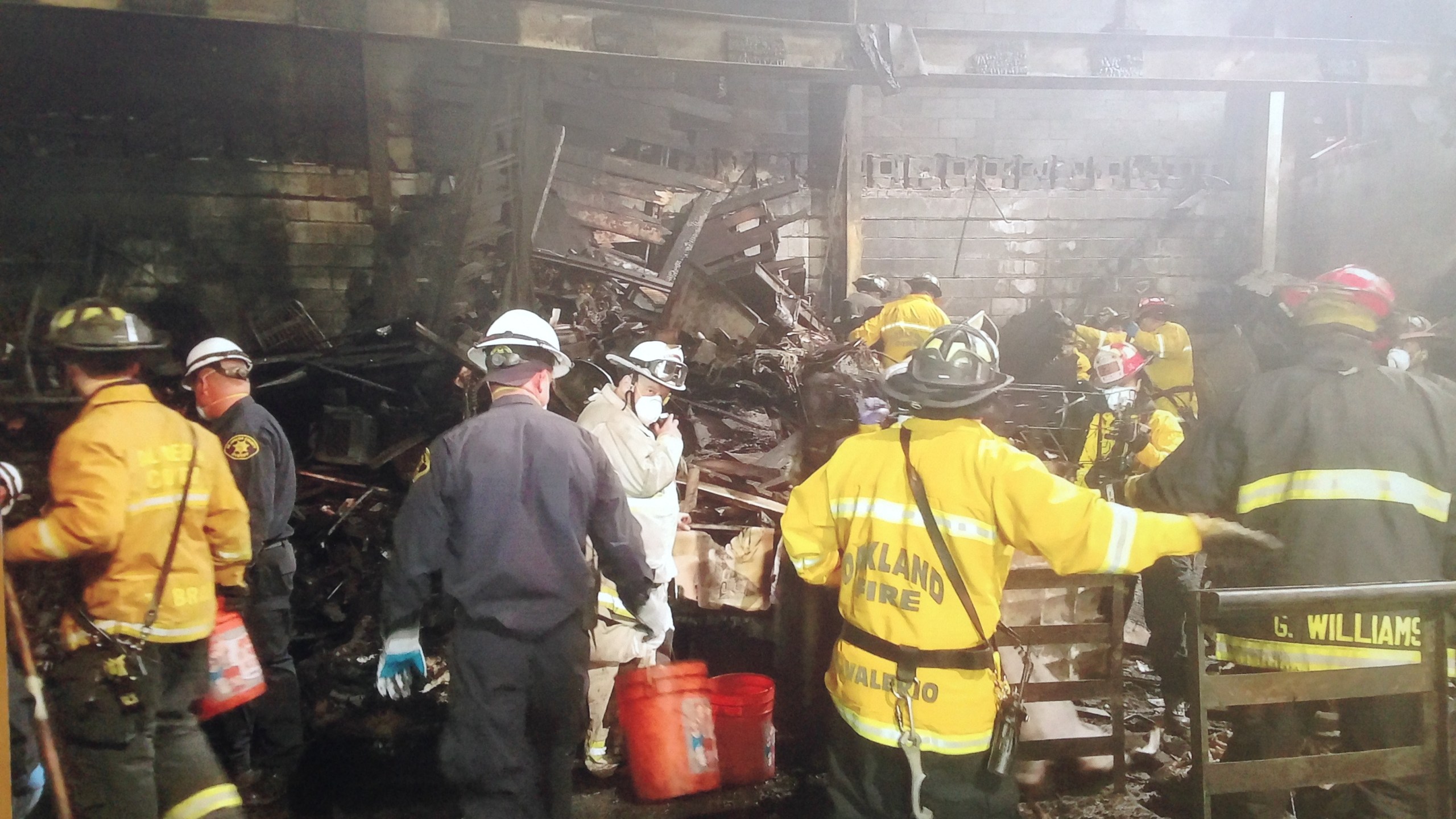 Firefighters work Dec. 5, 2016, in the burned shell of an Oakland warehouse where dozens of people died in a fire. (Credit: KTLA)