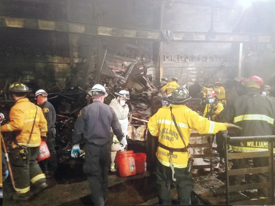 Firefighters work Dec. 5, 2016, in the burned shell of an Oakland warehouse where dozens of people died in a fire. (Credit: KTLA)