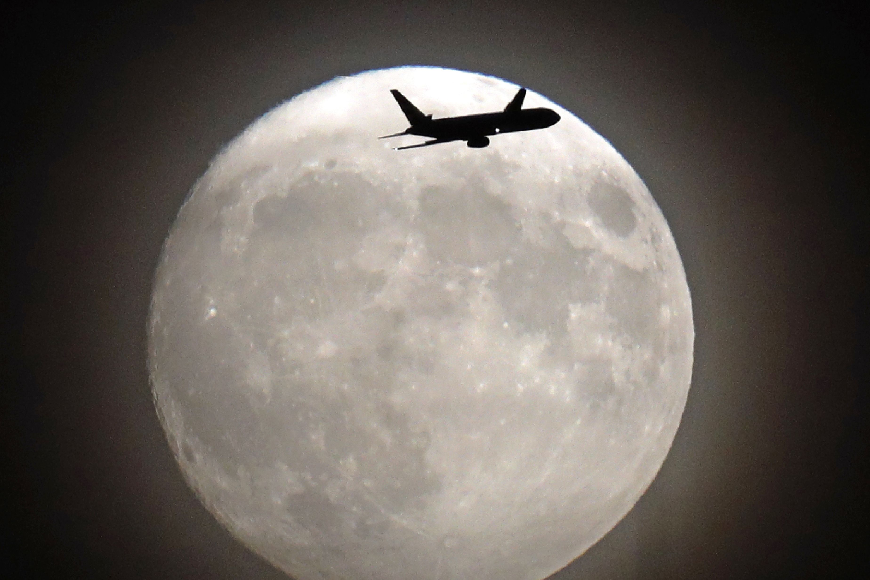 A commercial jet flies in front of the moon on its approach to Heathrow airport in west London on November 13, 2016. (Credit: ADRIAN DENNIS/AFP/Getty Images)