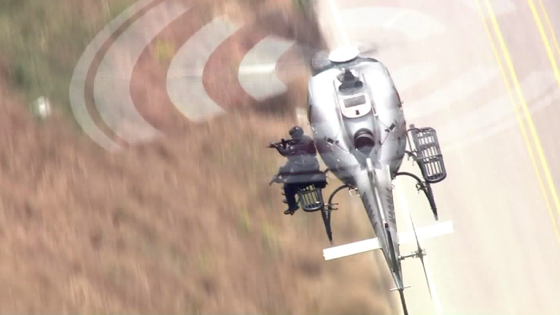 An LAPD officer points a firearm from a helicopter at the scene of a standoff in Sunland on May 8, 2017. (Credit: KTLA)