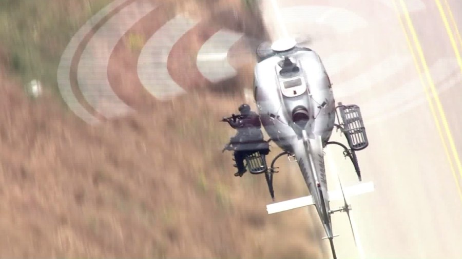 An LAPD officer points a firearm from a helicopter at the scene of a standoff in Sunland on May 8, 2017. (Credit: KTLA)