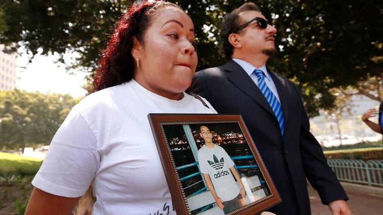 Teresa Dominguez holds a photo of her son, 14-year-old Jesse Romero, next to attorney Humberto Guizar as they hold a news conference to discuss a federal lawsuit filed against the city in the shooting death on June 23, 2017. (Credit: Al Seib / Los Angeles Times)