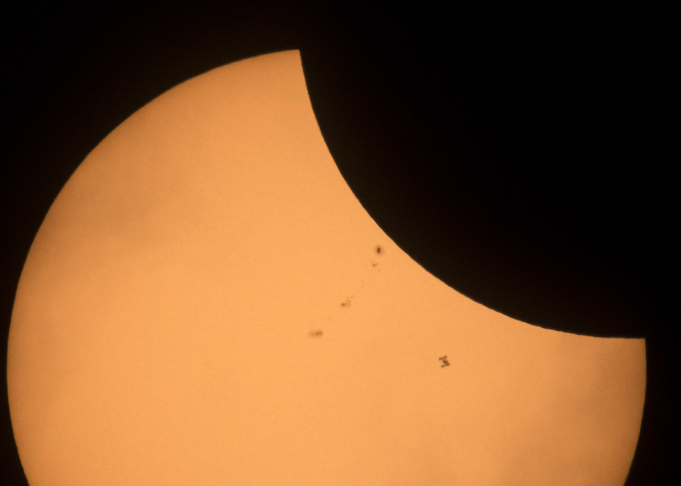 The International Space Station (bottom right), with a crew of six onboard, is seen in silhouette as it transits the sun at roughly five miles per second during a partial solar eclipse, Aug. 21, 2017, near Banner, Wyoming. (Credit: Joel Kowsky/NASA via Getty Images)