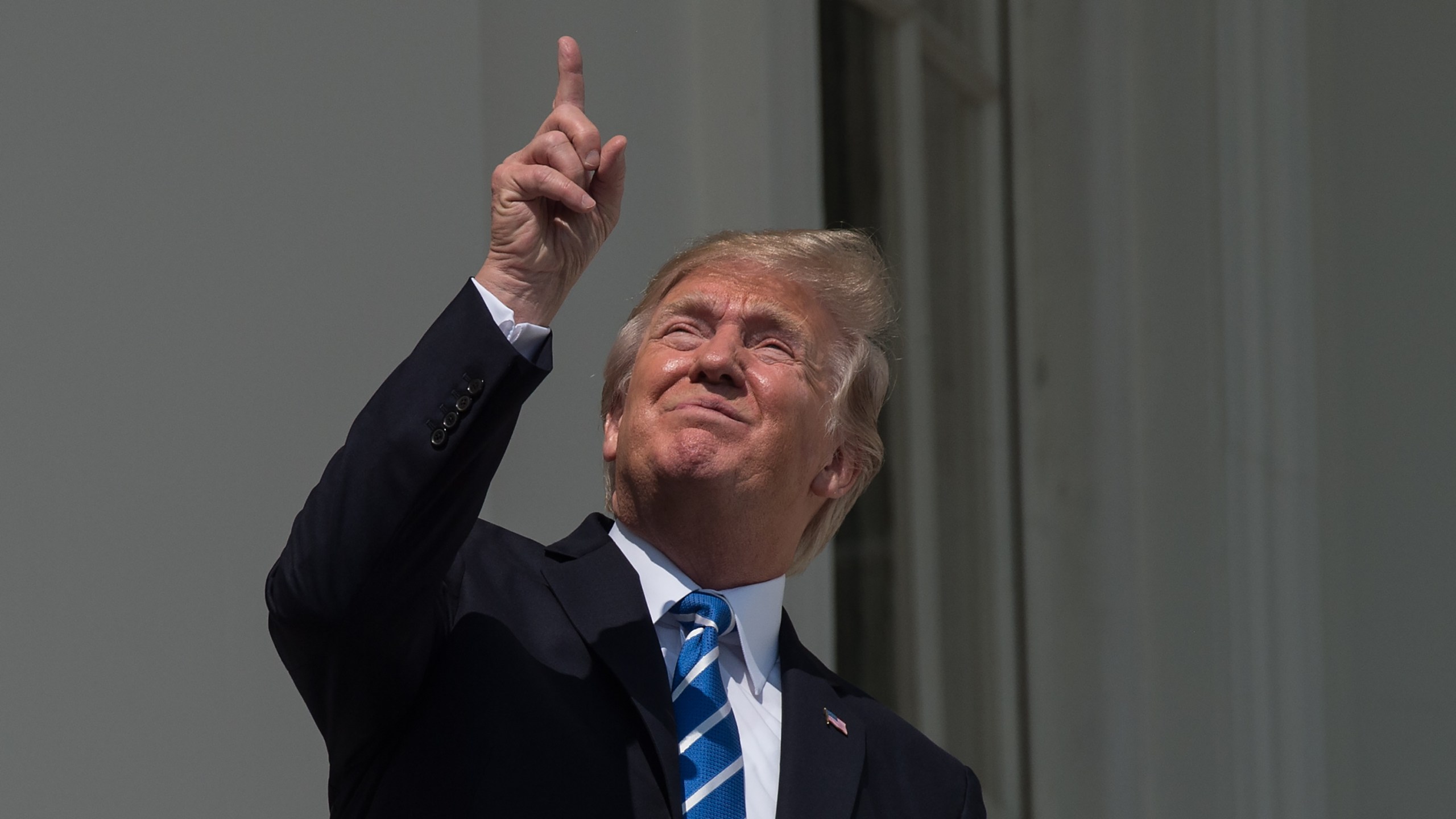 US President Donald Trump looks up at the partial solar eclipse from the balcony of the White House in Washington, DC, on August 21, 2017. (Credit: NICHOLAS KAMM/AFP/Getty Images)