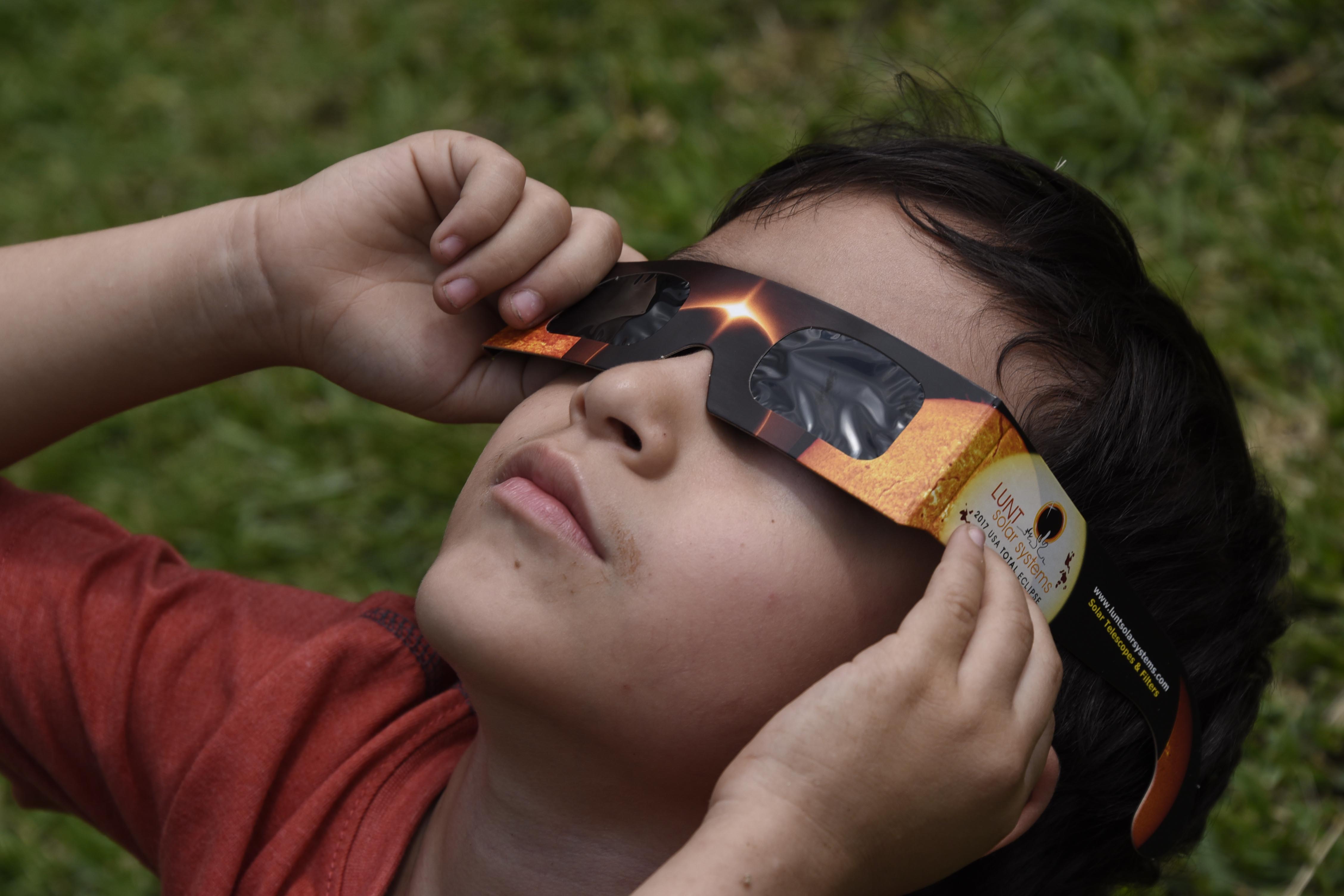 People visiting to Miraflores Museum watch the partial solar eclipse through special glasses, in Guatemala City on August 21, 2017. (Credit: JOHAN ORDONEZ/AFP/Getty Images)