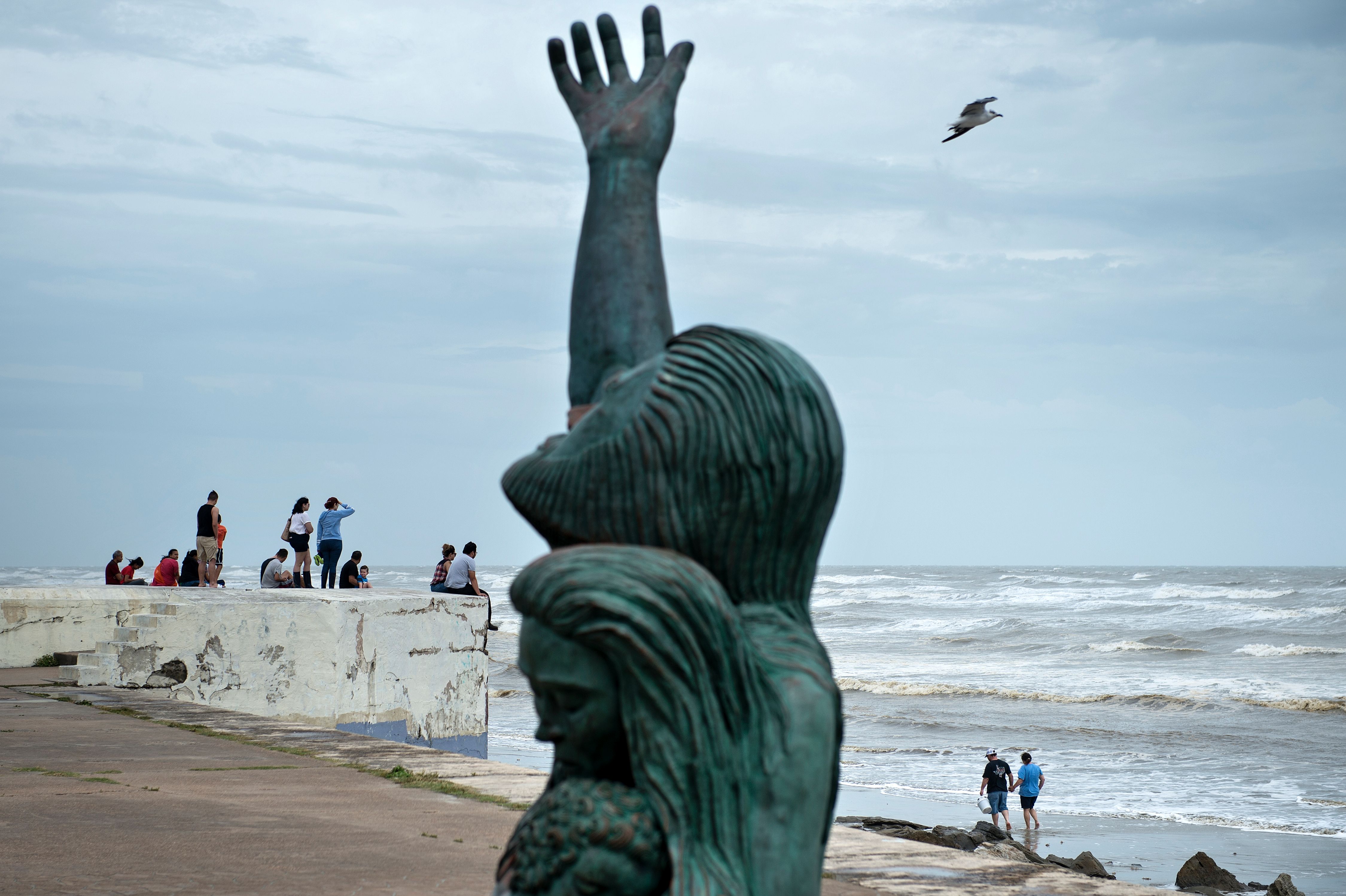 People look out from a seawall to the Gulf of Mexico as the effects of Hurricane Harvey are seen Aug. 26, 2017, in Galveston, Texas. (Credit: Brendan Smialowski / AFP / Getty Images)