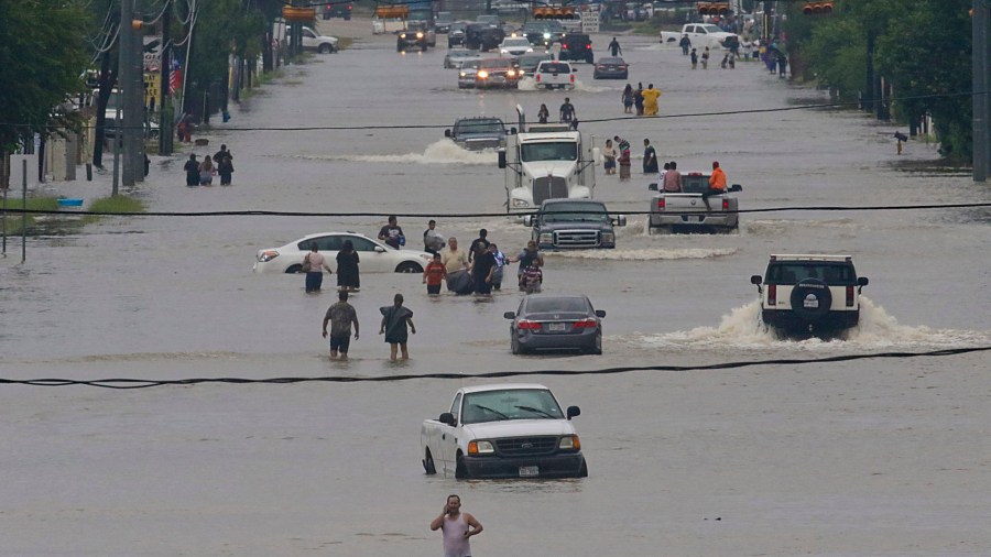 People walk through the flooded waters of Telephone Rd. in Houston on August 27, 2017 after Tropical Storm Harvey wreaks havoc on the region.(Credit: THOMAS B. SHEA/AFP/Getty Images)