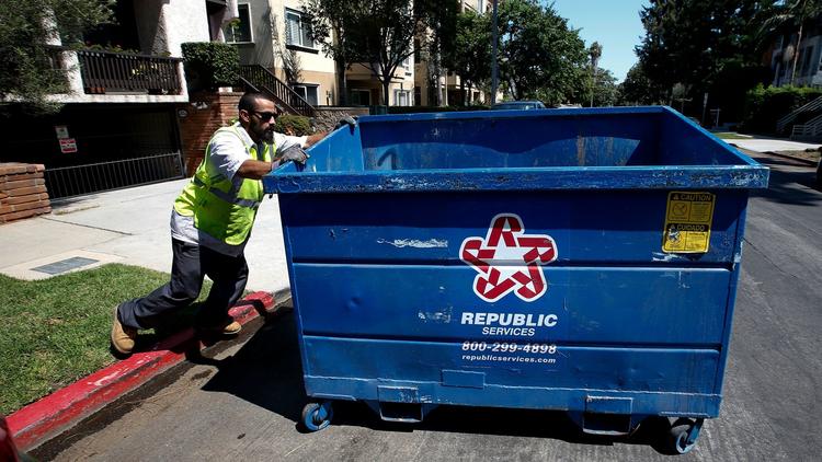 An employee with the trash hauler Athens Services moves a refuse bin outside a 14-unit condominium building in West Los Angeles. (Credit: Mel Melcon / Los Angeles Times)