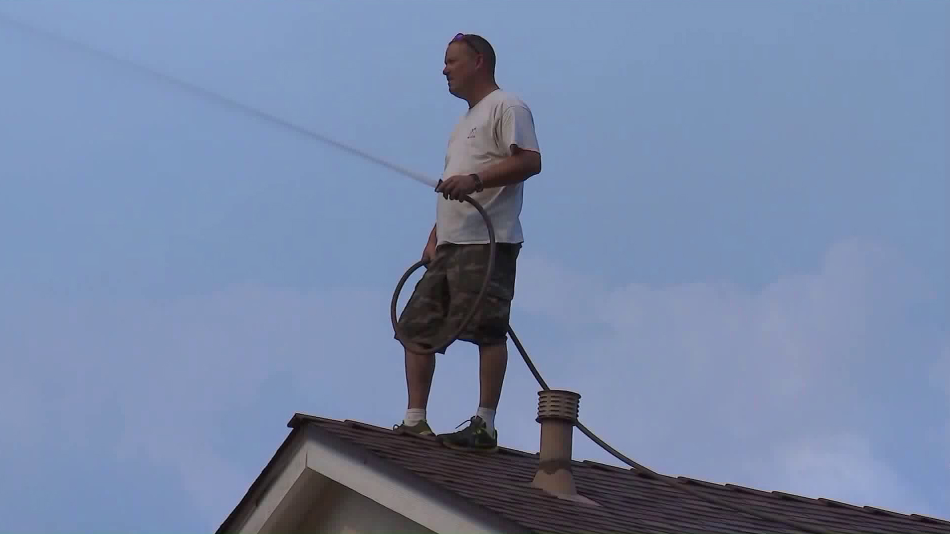 A resident of McGroarty Terrace in Tujunga sprays down his and his neighbors' homes in attempt to protect them from fire damage. (Credit: KTLA)