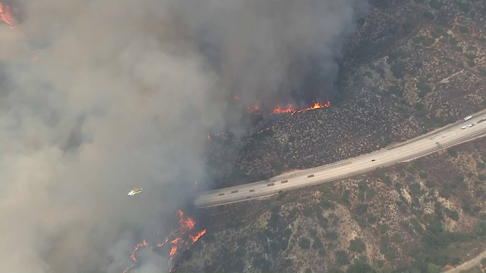 A helicopter crosses in front of a huge plume of smoke from a wildfire in Tujunga on Sept. 1, 2017. (Credit: KTLA)