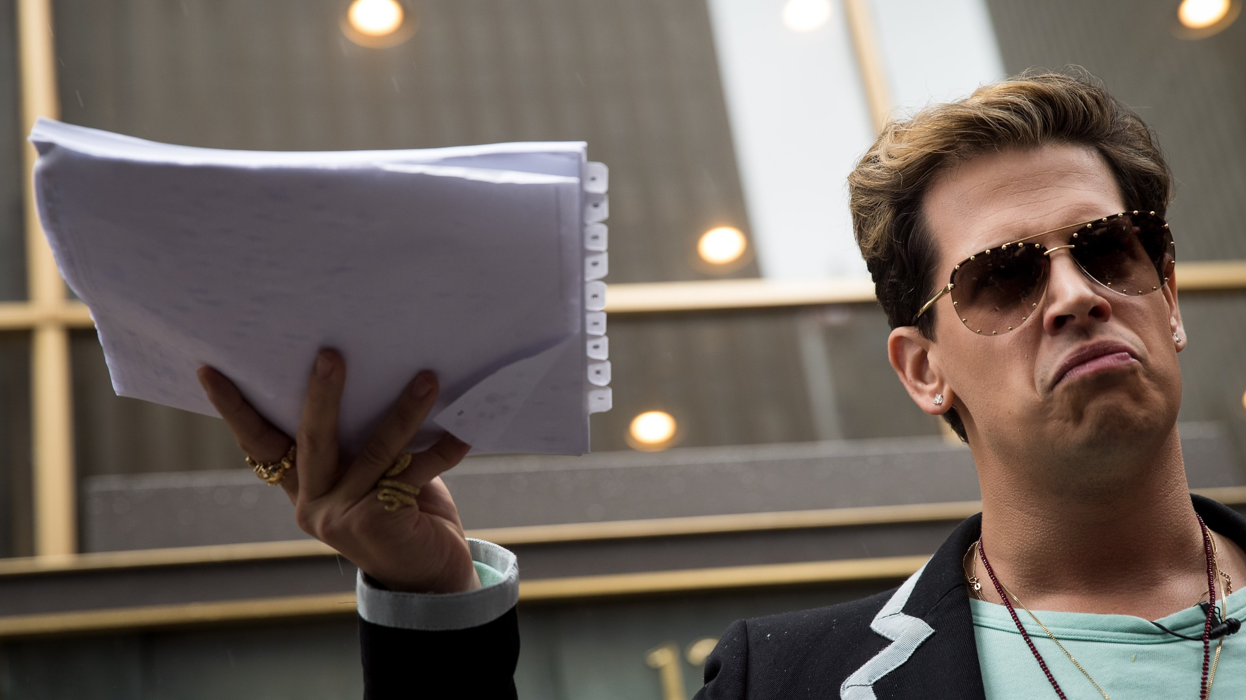 Milo Yiannopoulos holds up a copy of a legal complaint as he speaks outside the offices of Simon & Schuster publishing company after it canceled his book deal, July 7, 2017, in New York City. (Credit: Drew Angerer/Getty Images)