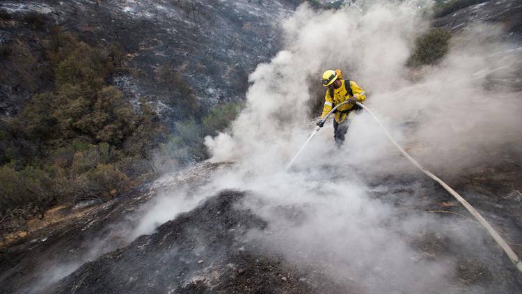 L.A. County firefighter Kevin Sleight extinguishes hot spots while battling the La Tuna fire along Crestline Drive in Los Angeles on Sept. 3, 2017. (Credit: Allen J. Schaben / Los Angeles Times)