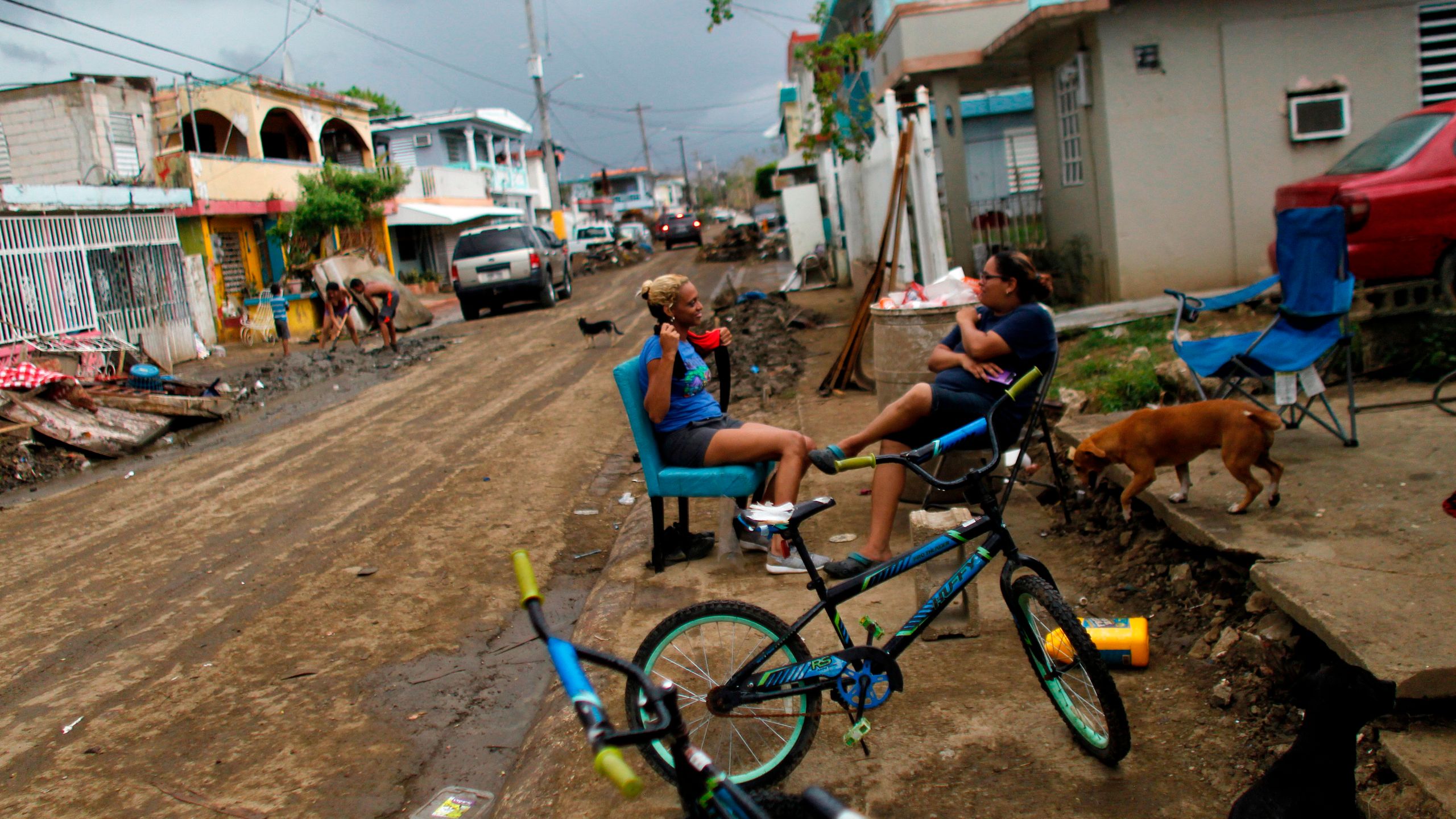 Two women chat on a sidewalk in an area affected by Hurricane Maria in Toa Baja, Puerto Rico, on Oct. 5, 2017. (Credit: Ricardo Arduengo / AFP / Getty Images)