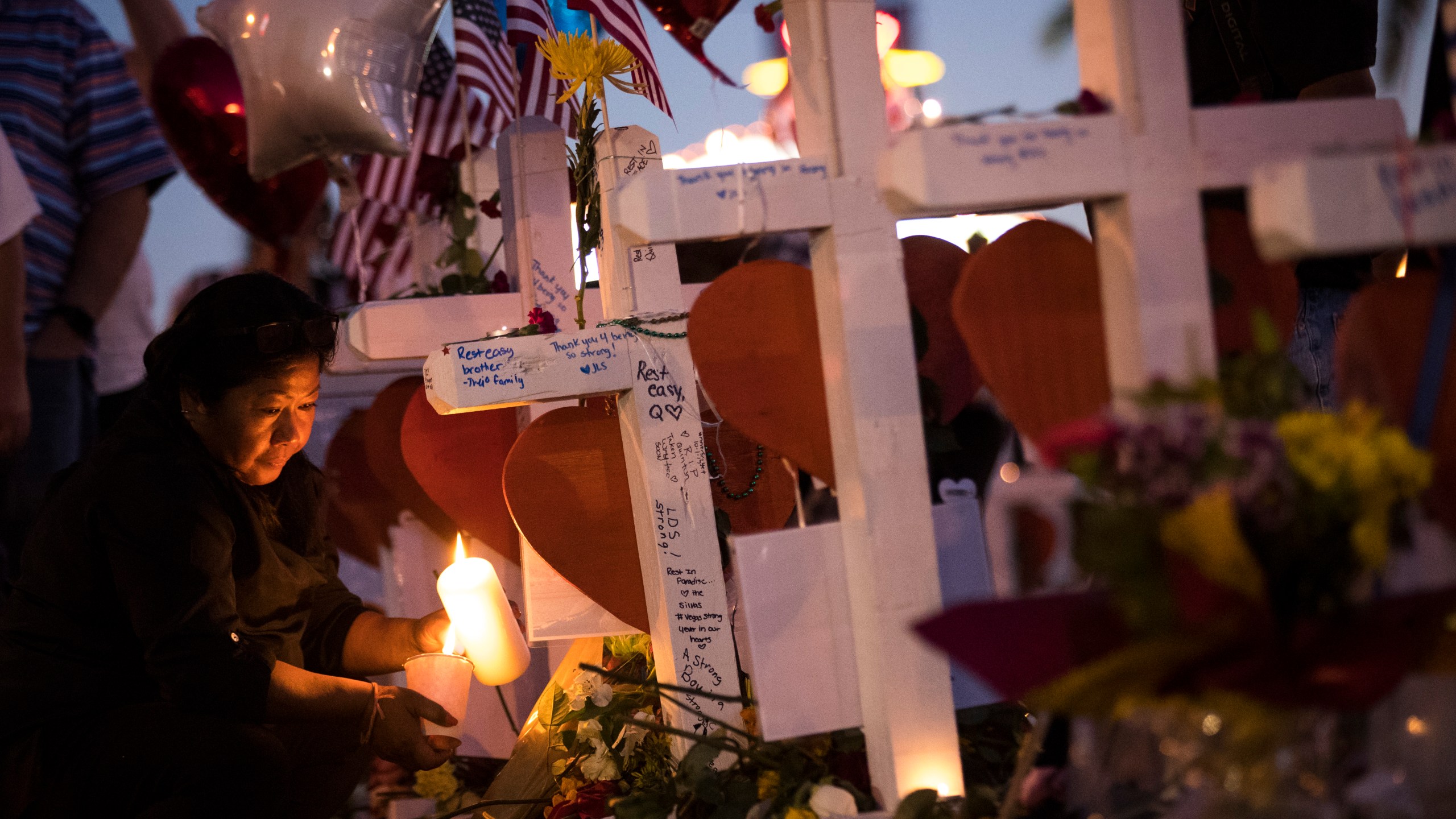 A woman lights candles at several of the 58 white crosses at a makeshift memorial on the south end of the Las Vegas Strip, Oct. 6, 2017 in Las Vegas, Nevada. (Credit: Drew Angerer / Getty Images)