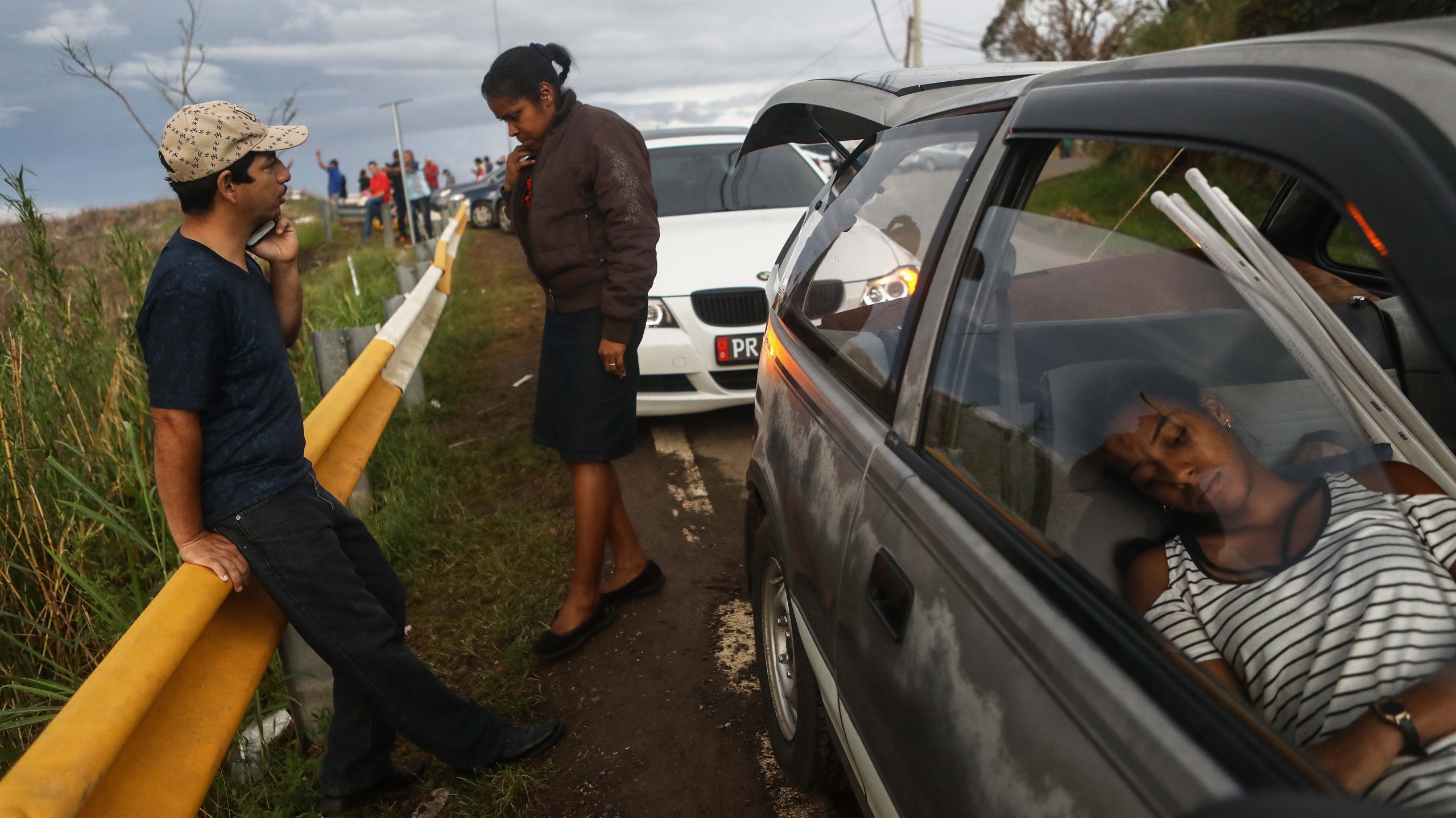 Family members gather while attempting to speak by phone with another family member along a roadside near the top of a mountain in Orocovis, more than two weeks after Hurricane Maria swept through Puerto Rico, on Oct. 6, 2017. (Credit: Mario Tama / Getty Images)