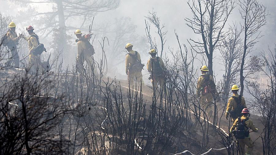 Firefighters cut a path through charred terrain as they work Oct. 17, 2017, to extinguish a fire that scorched the area near Mount Wilson. (Credit: Irfan Khan / Los Angeles Times)