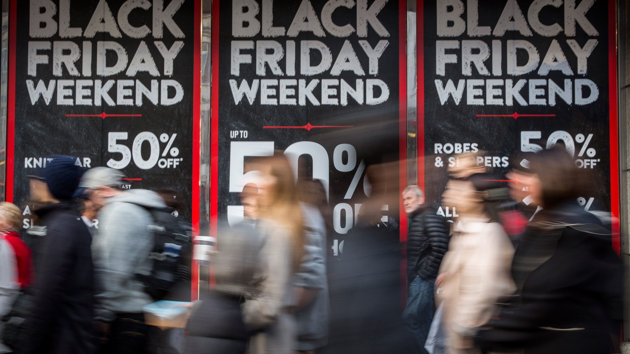 People walk past a shopfront on Oxford Street advertising 'Black Friday' discounts on November 28, 2014 in London, England. (Credit: Rob Stothard/Getty Images)