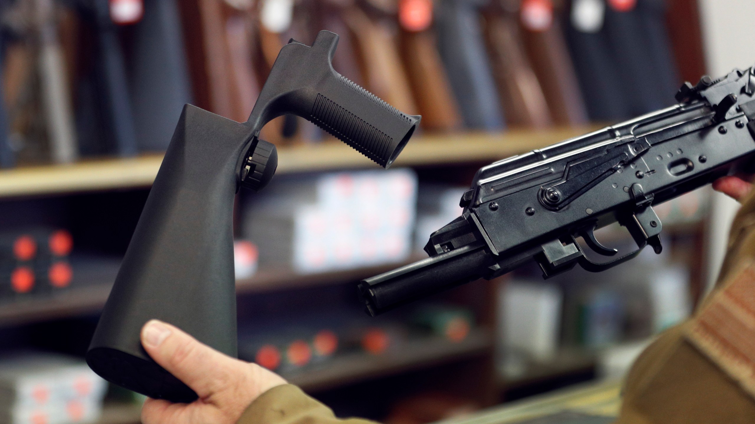 A bump stock device (left), is shown next to a AK-47 semi-automatic rifle (right). (Credit: George Frey/Getty Images)