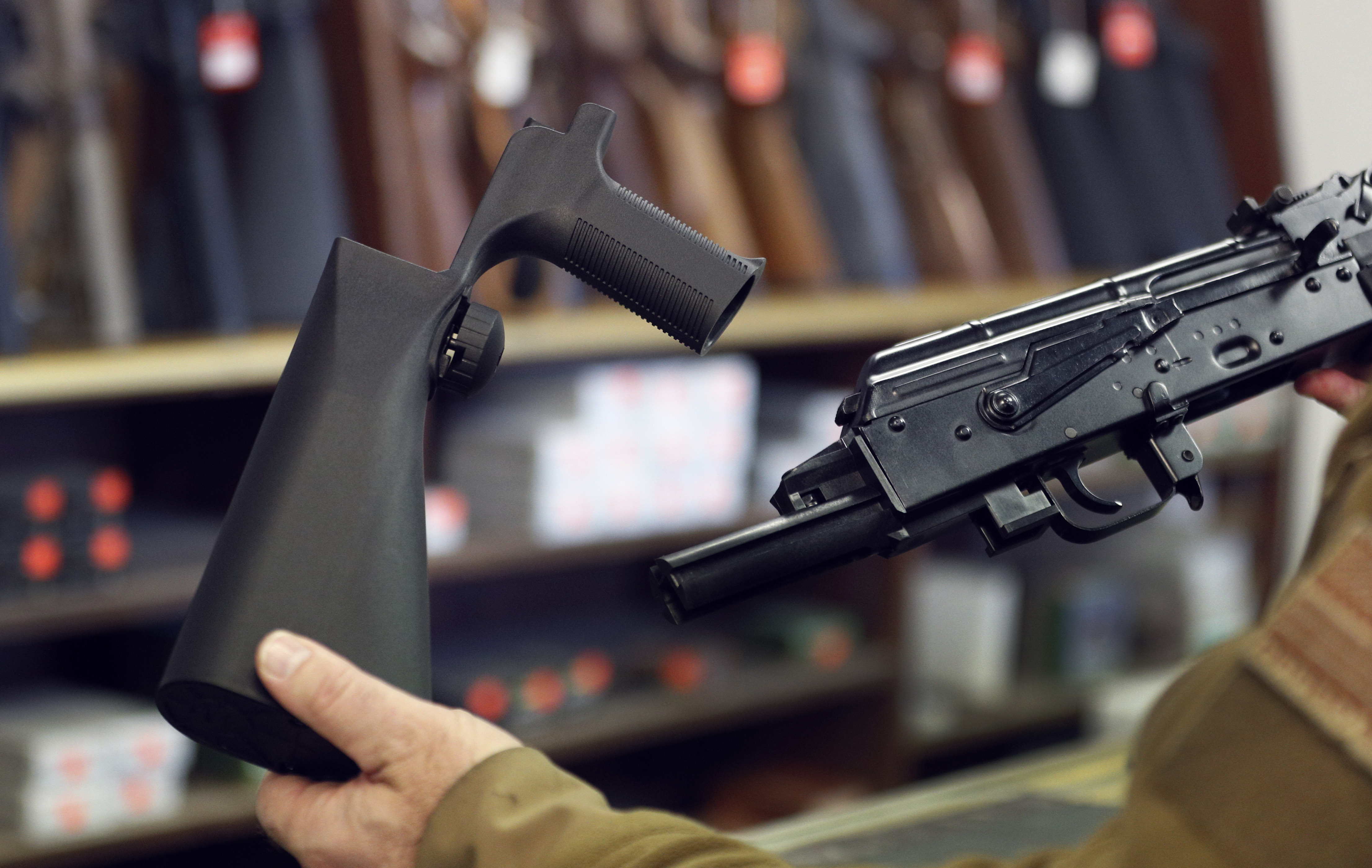 A bump stock device (left), is shown next to a AK-47 semi-automatic rifle (right). (Credit: George Frey/Getty Images)