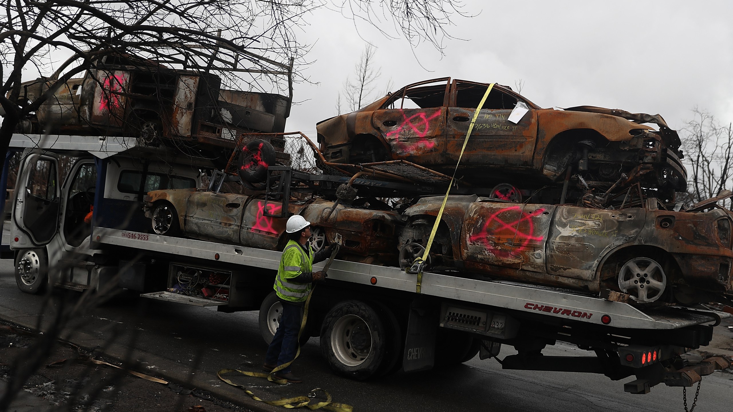 A worker secures burned-out cars onto a truck in the Coffey Park neighborhood of Santa Rosa on Nov. 13, 2017. (Credit: Justin Sullivan / Getty Images)