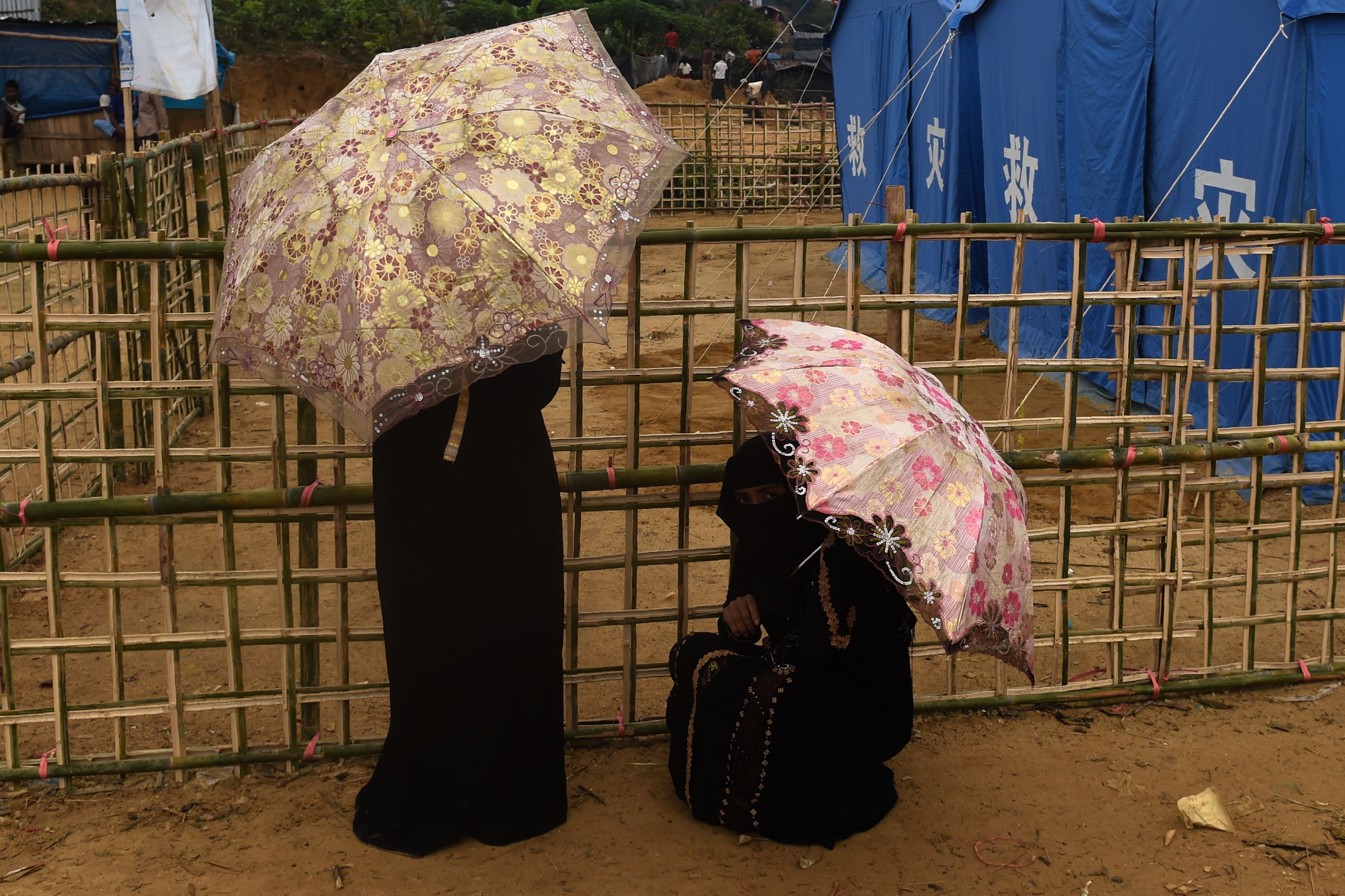 Rohingya refugee women rest with umbrella during a drizzle at Thankhali refugee camp in the Bangladeshi district of Ukhia on Nov. 17, 2017. (Credit: Munir Uz Zaman / AFP / Getty Images)