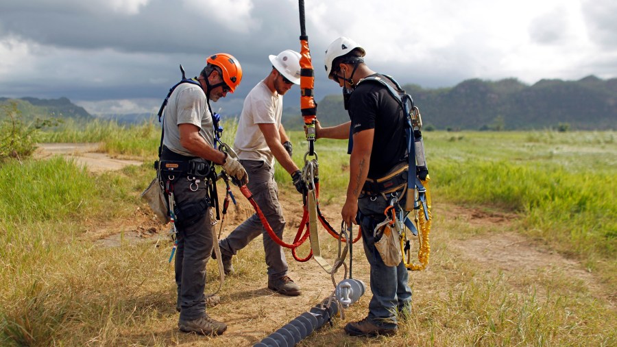 Whitefish Energy Holdings workers repair power line towers after Hurricane Maria in Manati, Puerto Rico on October 31, 2017. (Credit: Ricardo Arduengo/AFP/Getty Images)