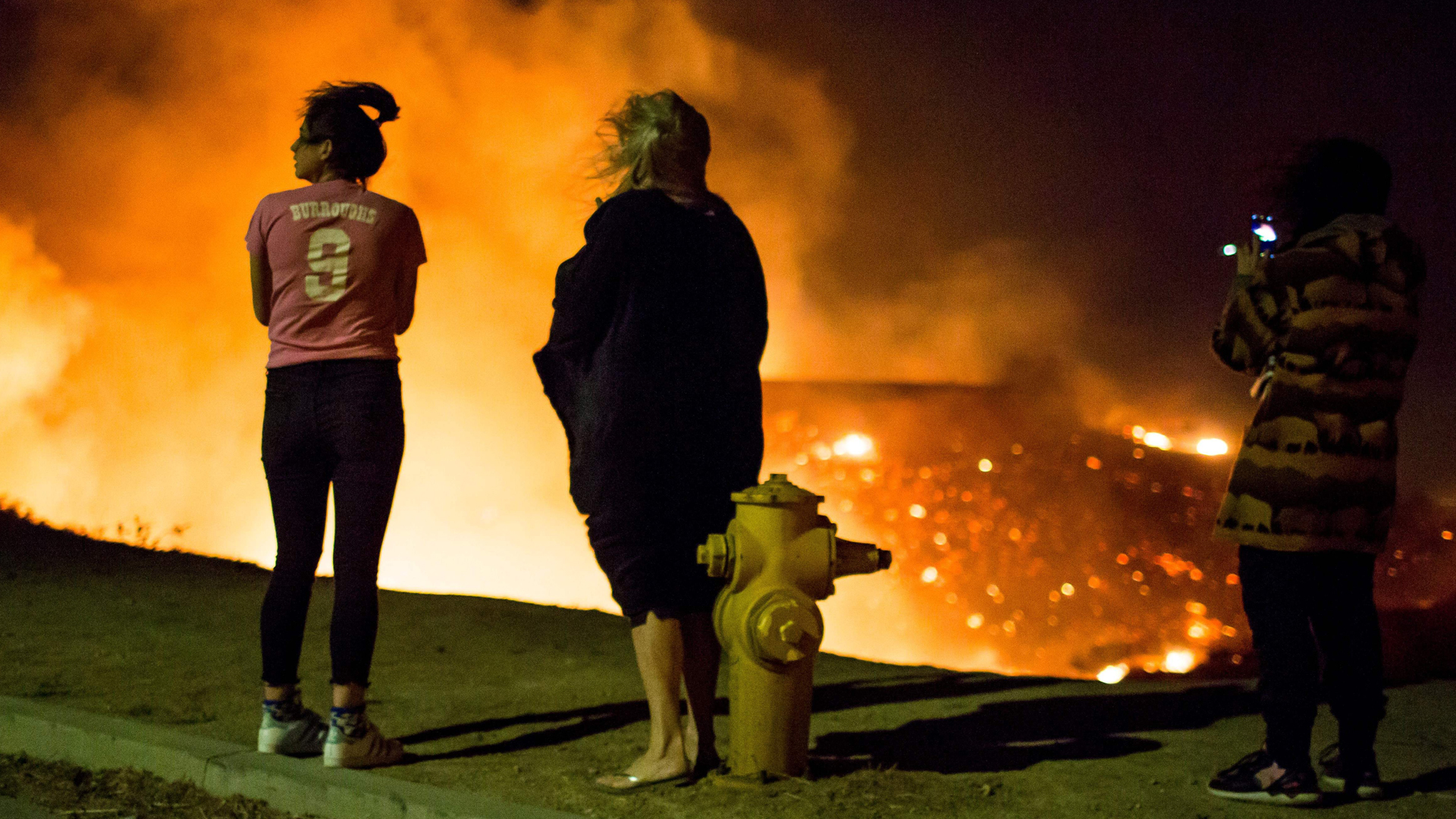 Residents watch as the Creek Fire burns along a hillside near homes in the Shadow Hills neighborhood of Los Angeles on Dec. 5, 2017. (Credit: Kyle Grillot/AFP/Getty Images)