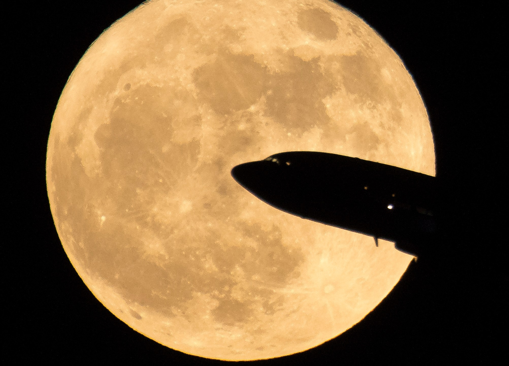 In this handout provided by NASA, an aircraft taking off from Ronald Reagan National Airport is seen passing in front of the moon as it rises on December 3, 2017 in Washington, DC. (Credit: NASA/Bill Ingalls via Getty Images)