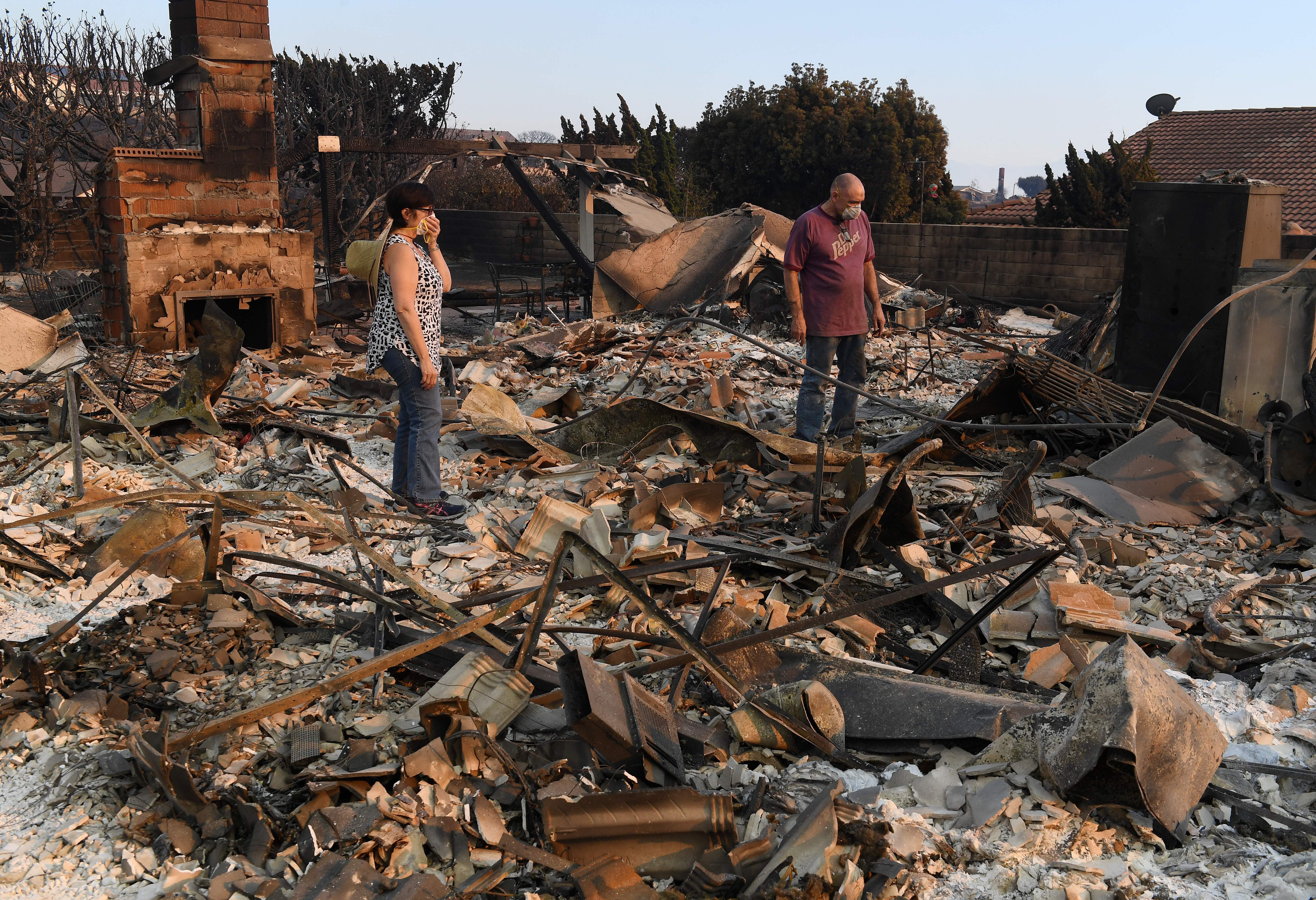 John and Julie Wilson sort through the remnants of their burnt out home after the Thomas Fire swept through Ventura on Dec. 6, 2017. (Credit: AFP PHOTO / MARK RALSTON)