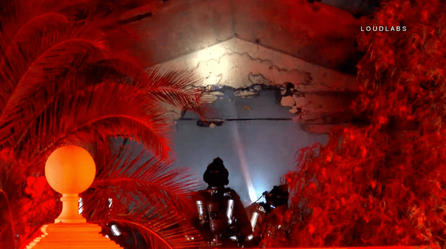 Firefighters survey the damage after a car crashed into a Corona home and caught it on fire on Dec. 18, 2017. (Credit: LoudLabs)