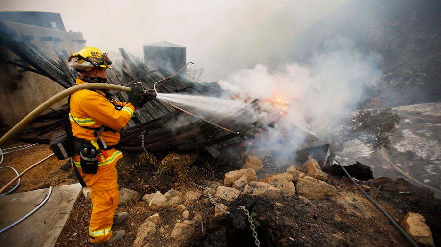 Firefighter Chris Black with the Sacramento Fire Department douses flames Tuesday in Toro Canyon in Carpinteria. (Credit: Al Seib / Los Angeles Times)