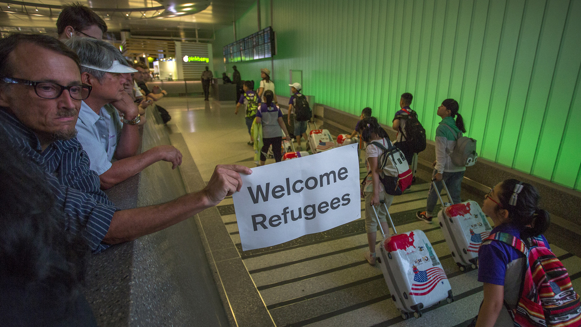 John Wider carries a welcome sign near arriving international travelers on the first day of the the partial reinstatement of the Trump travel ban, temporarily barring travelers from six Muslim-majority nations from entering the U.S., at Los Angeles International Airport (LAX) on June 29, 2017, in Los Angeles. (Credit: David McNew/Getty Images)