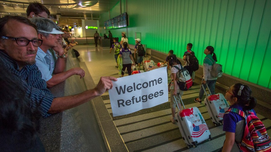 John Wider carries a welcome sign near arriving international travelers on the first day of the the partial reinstatement of the Trump travel ban, temporarily barring travelers from six Muslim-majority nations from entering the U.S., at Los Angeles International Airport (LAX) on June 29, 2017, in Los Angeles. (Credit: David McNew/Getty Images)