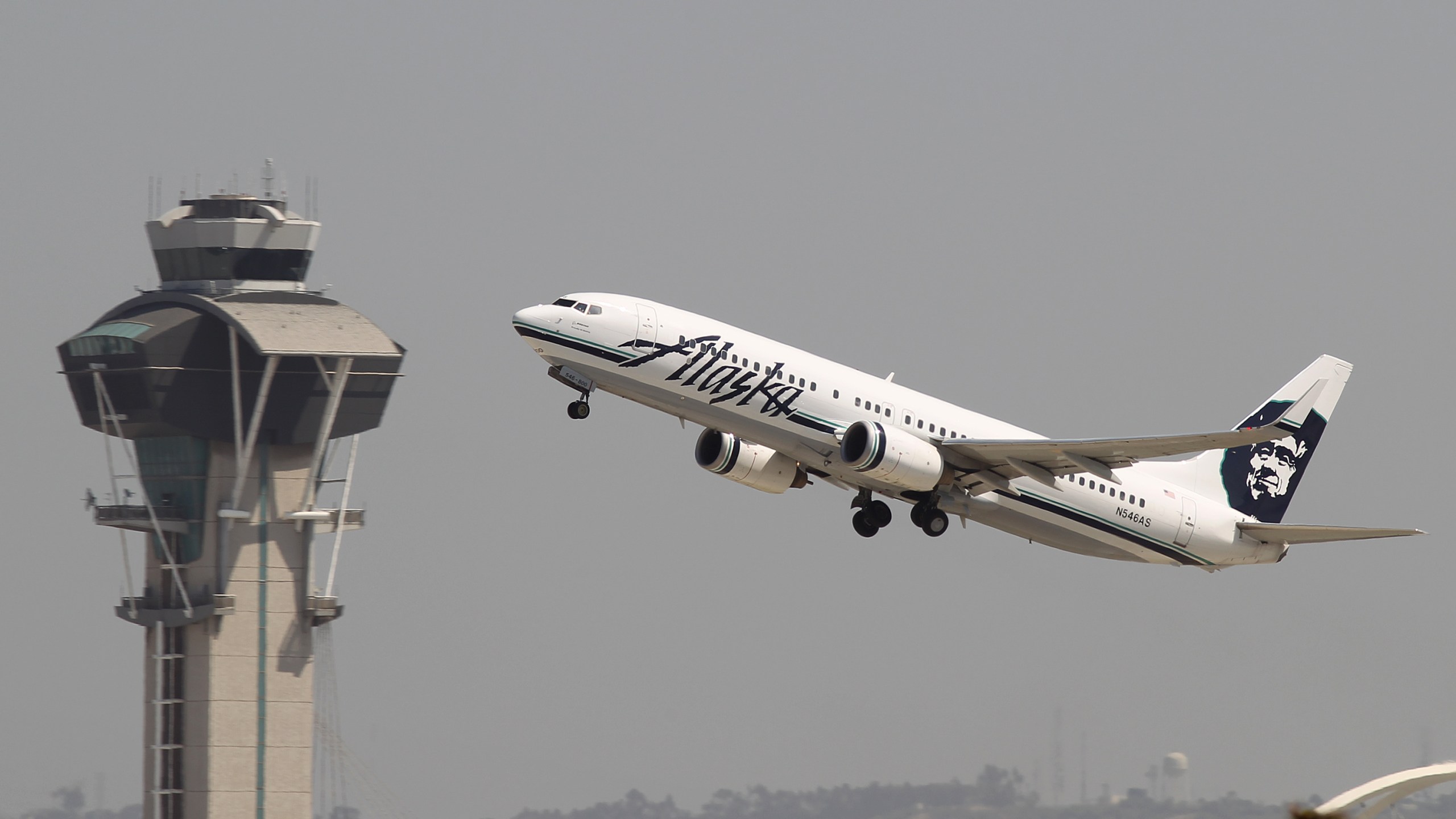 An Alaska Airlines jet passes the air traffic control tower at Los Angeles International Airport during take-off on April 22, 2013. (Credit: David McNew/Getty Images)