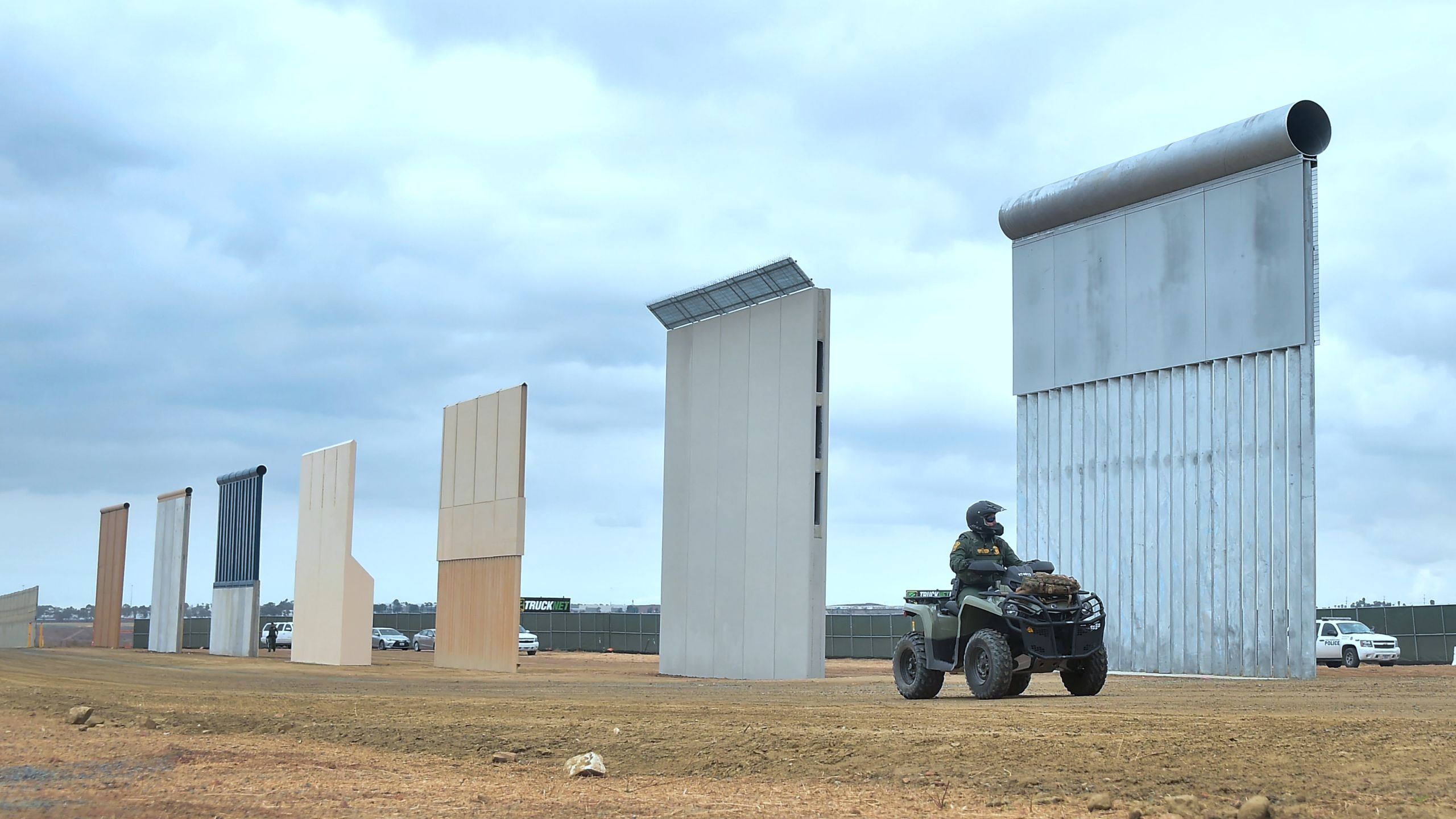 A Homeland Security border patrol officer rides an All Terrain Vehicle (ATV) past prototypes of President Donald Trump's proposed border wall on Nov. 1, 2017, in Otay Mesa. (Credit: Frederic J. Brown / AFP / Getty Images)