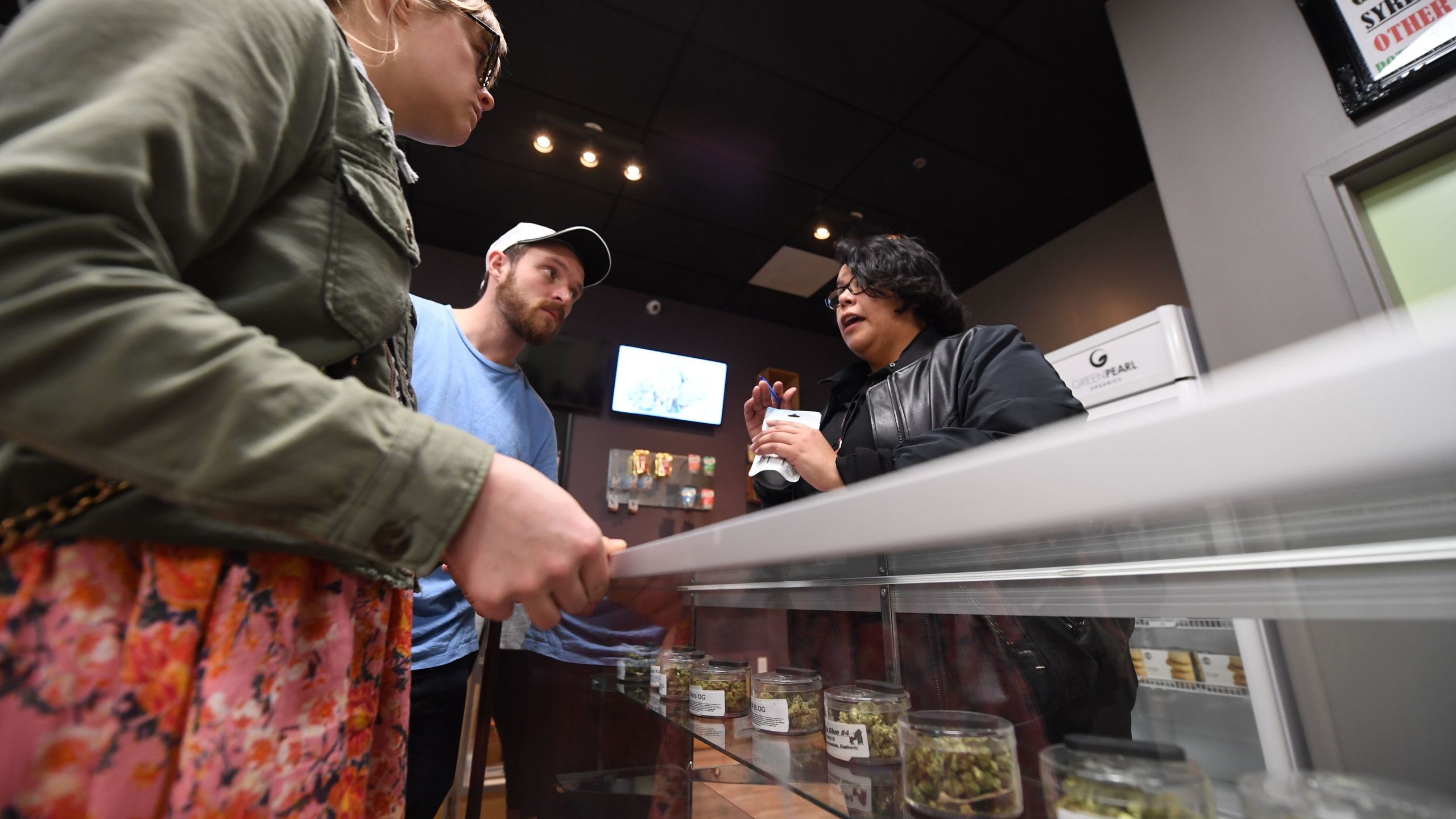 Tourists Laura Torgerson and Ryan Sheehan, visiting from Arizona, talk to a budtender at the Green Pearl Organics dispensary on the first day of legal recreational marijuana sales in California on Jan. 1, 2018 in Desert Hot Springs. (Credit: ROBYN BECK/AFP/Getty Images)