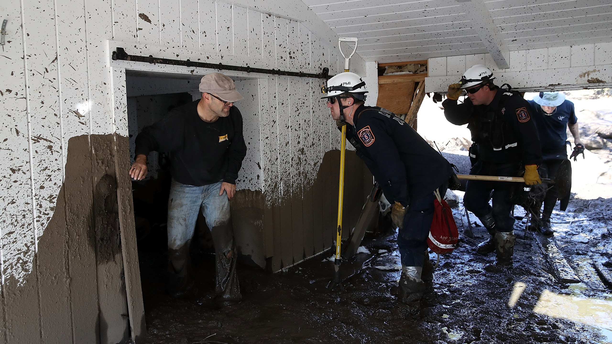 A search and rescue team checks in with people who are looking for salvageable items in a the home of a family member that was destroyed by a mudslide on Jan. 11, 2018, in Montecito. (Credit: Justin Sullivan/Getty Images)