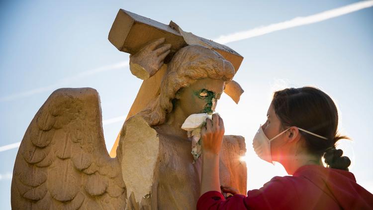 Evelyn Askew, 19, cleans an angel statue that was damaged and spray-painted with graffiti in front of Church of the Angels in Pasadena. (Credit: Jay L. Clendenin / Los Angeles Times)