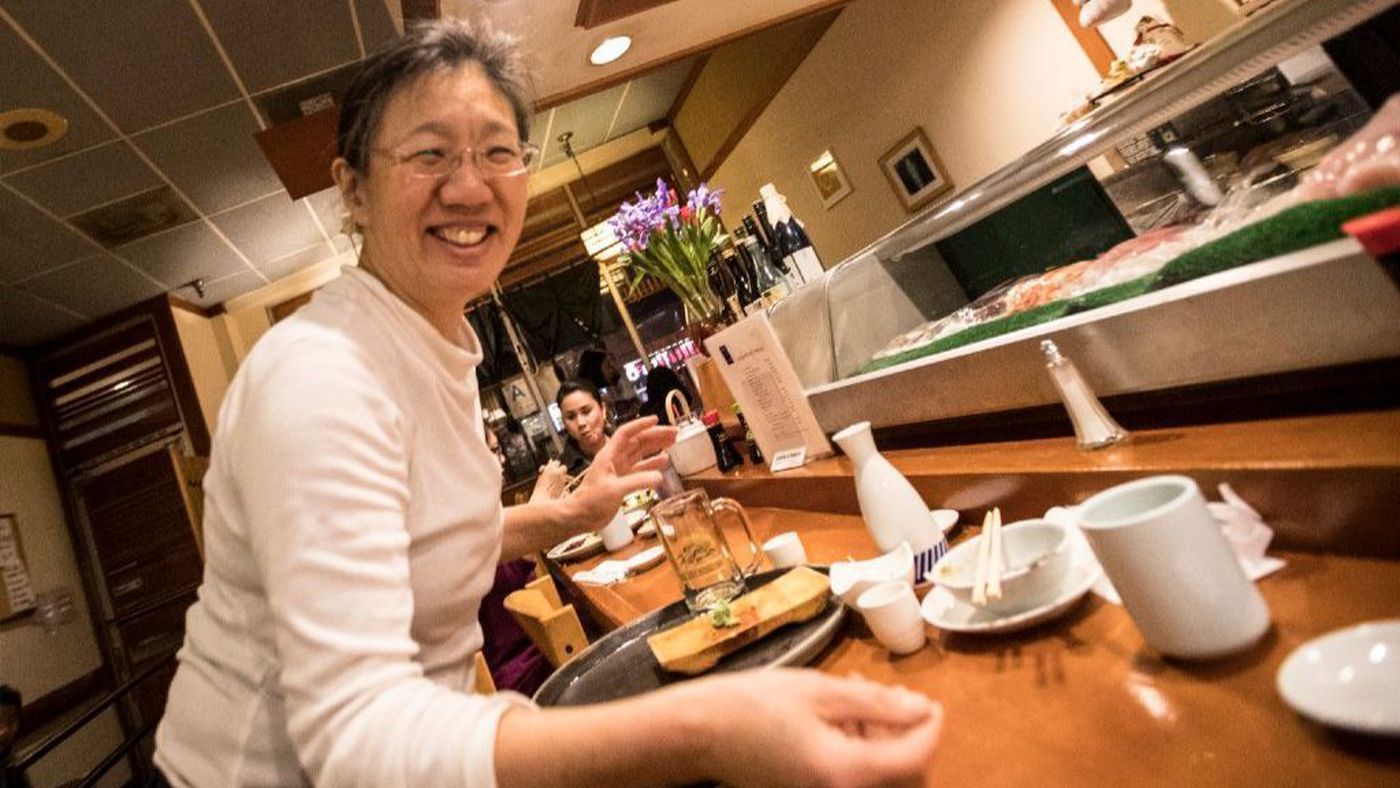 The mother of record-breaking Olympic skater Mirai Nagasu, Ikuko Nagasu, picks up dishes at a table at the family's Japanese restaurant Sushi Kiyosuzo in Arcadia in this undated photo. (Brian van der Brug / Los Angeles Times)