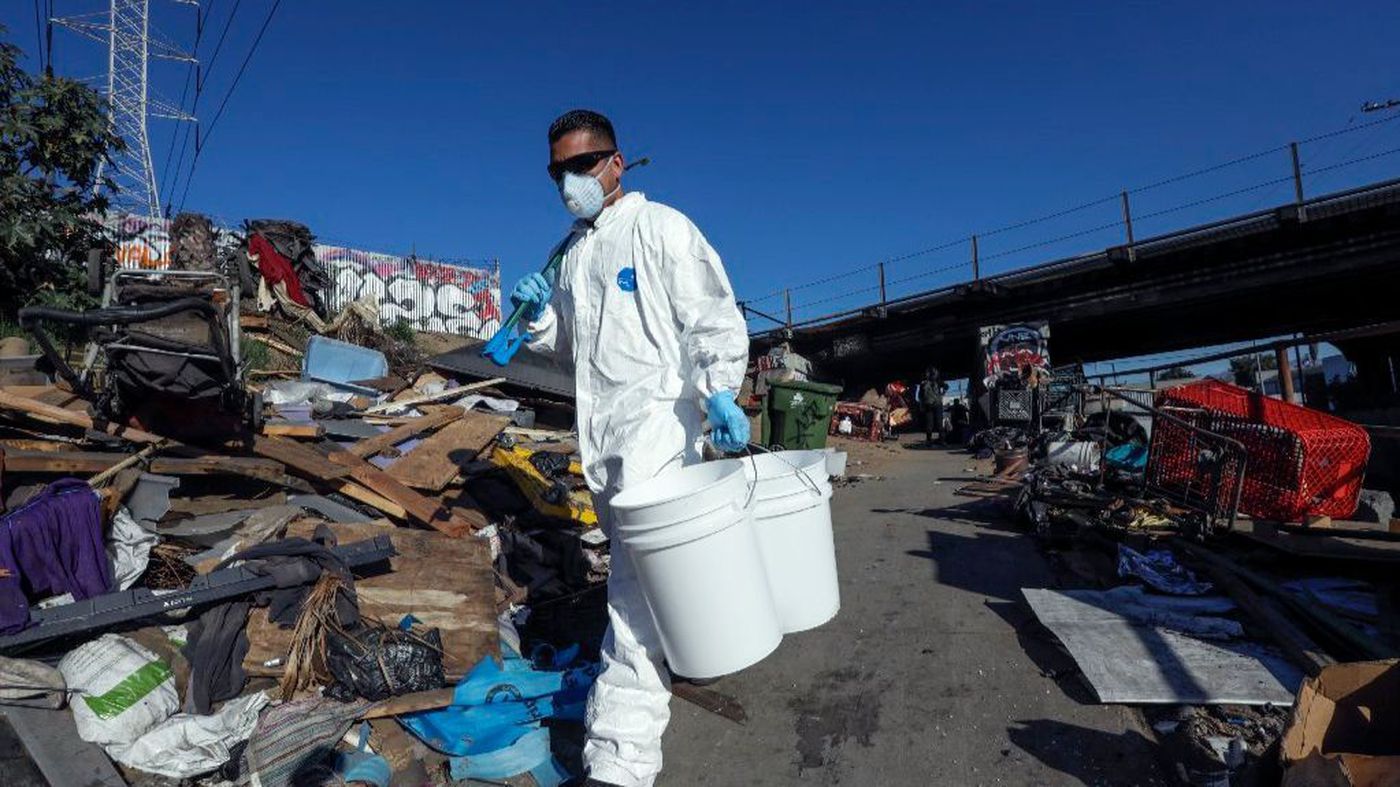 Miguel Munos, wearing protective gear and armed with a picker and buckets, looks for hazardous material at a homeless encampment cleanup in Boyle Heights in this undated photo. (Credit: Irfan Khan / Los Angeles Times)