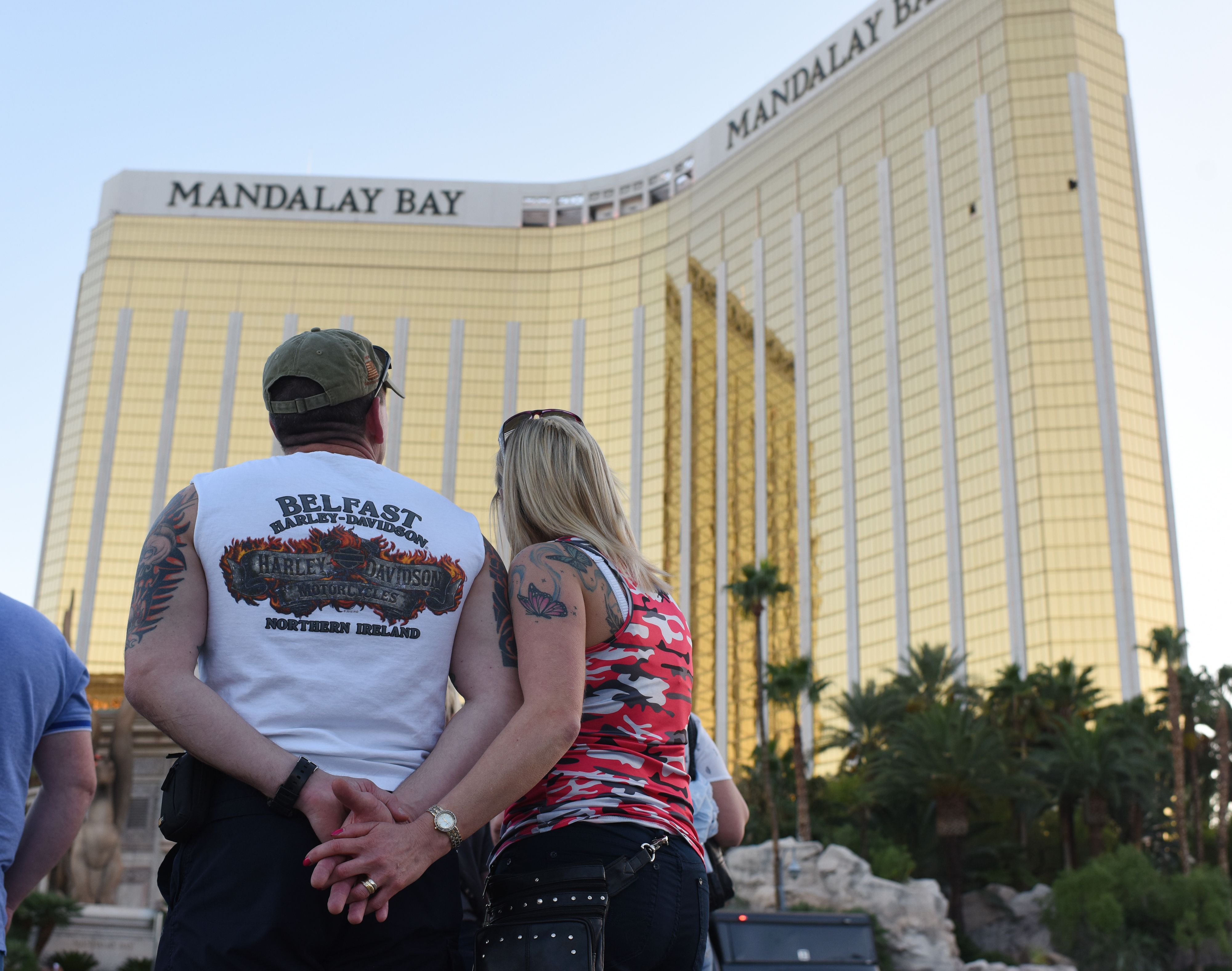 A couple stops on the Las Vegas Strip October 4, 2017, to look up at the two broken windows in the Mandalay Bay hotel from which killer Stephen Paddock let loose the worst mass shooting in modern American history. (Credit: ROBYN BECK/AFP/Getty Images)