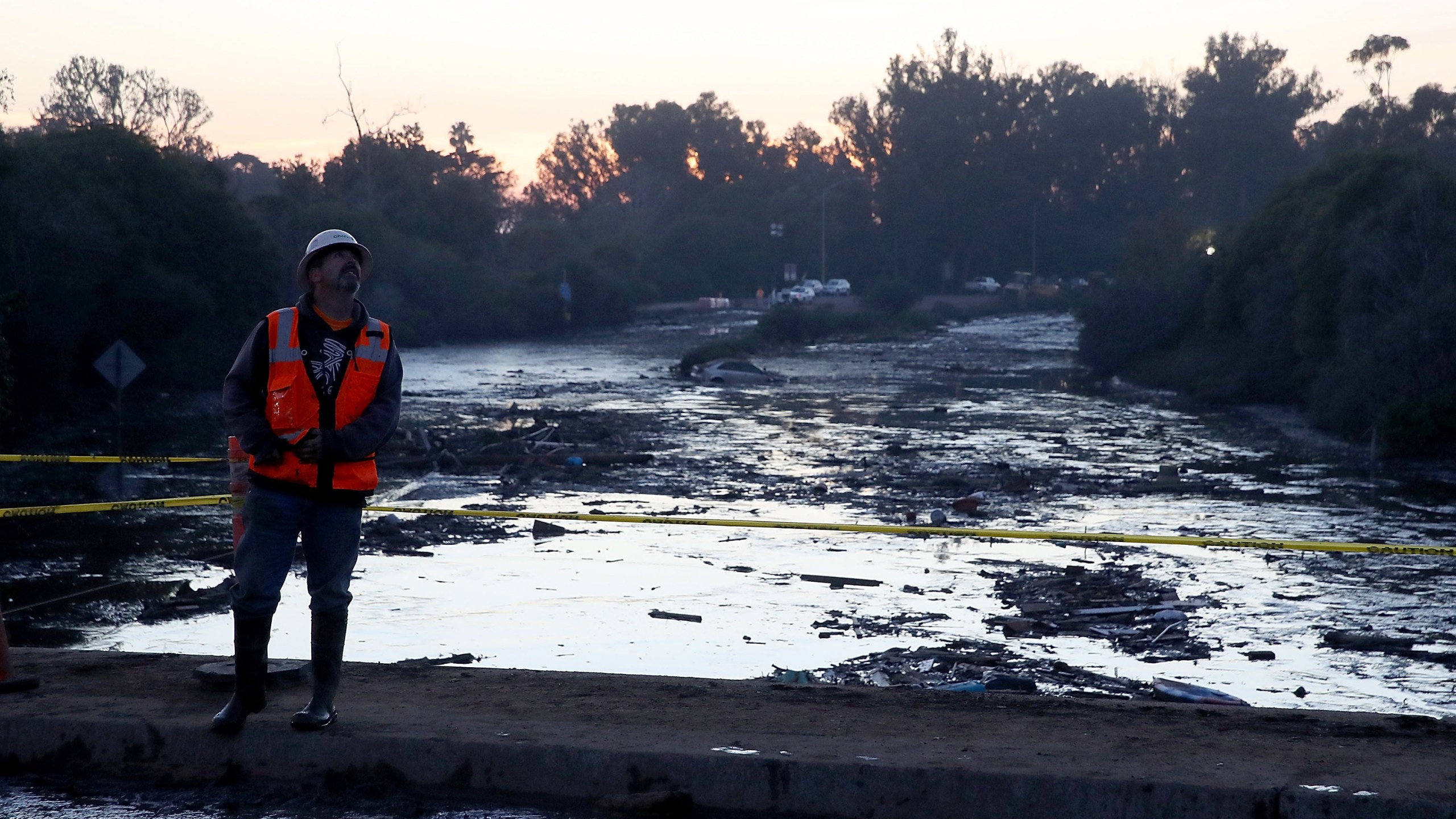 A worker monitors a crane as he stands on an overpass above a flooded section of the 101 Freeway on Jan. 11, 2018, in Montecito. (Credit: Justin Sullivan/Getty Images)