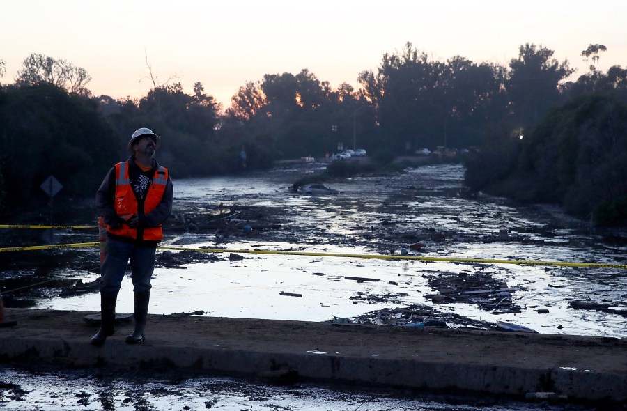 A worker monitors a crane as he stands on an overpass above a flooded section of the 101 Freeway on Jan. 11, 2018, in Montecito. (Credit: Justin Sullivan/Getty Images)