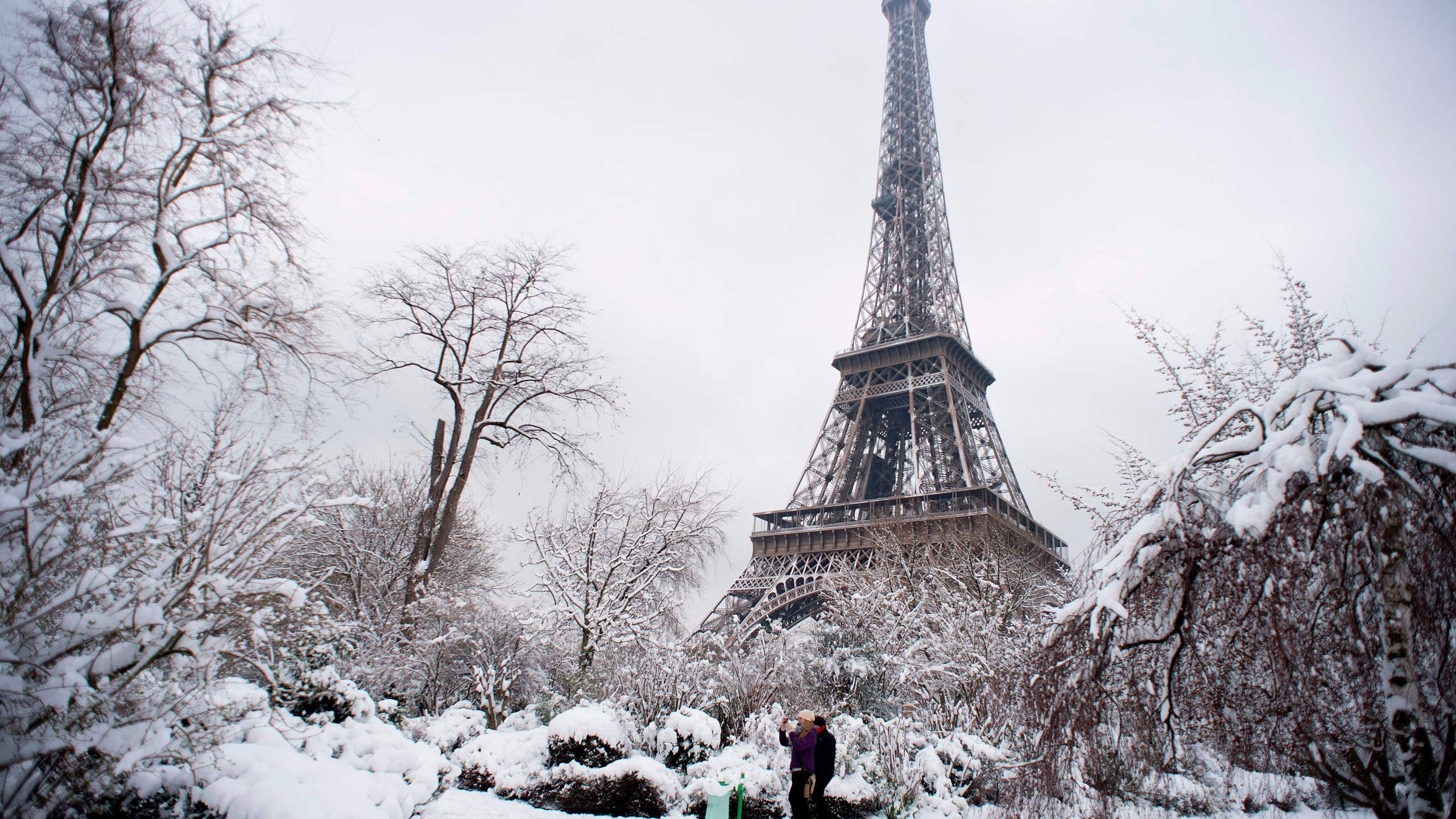 People walk through the snow covered Champ de Mars garden near the Eiffel tower on February 7, 2018 following heavy snowfall in Paris. (Credit: ALAIN JOCARD/AFP/Getty Images)