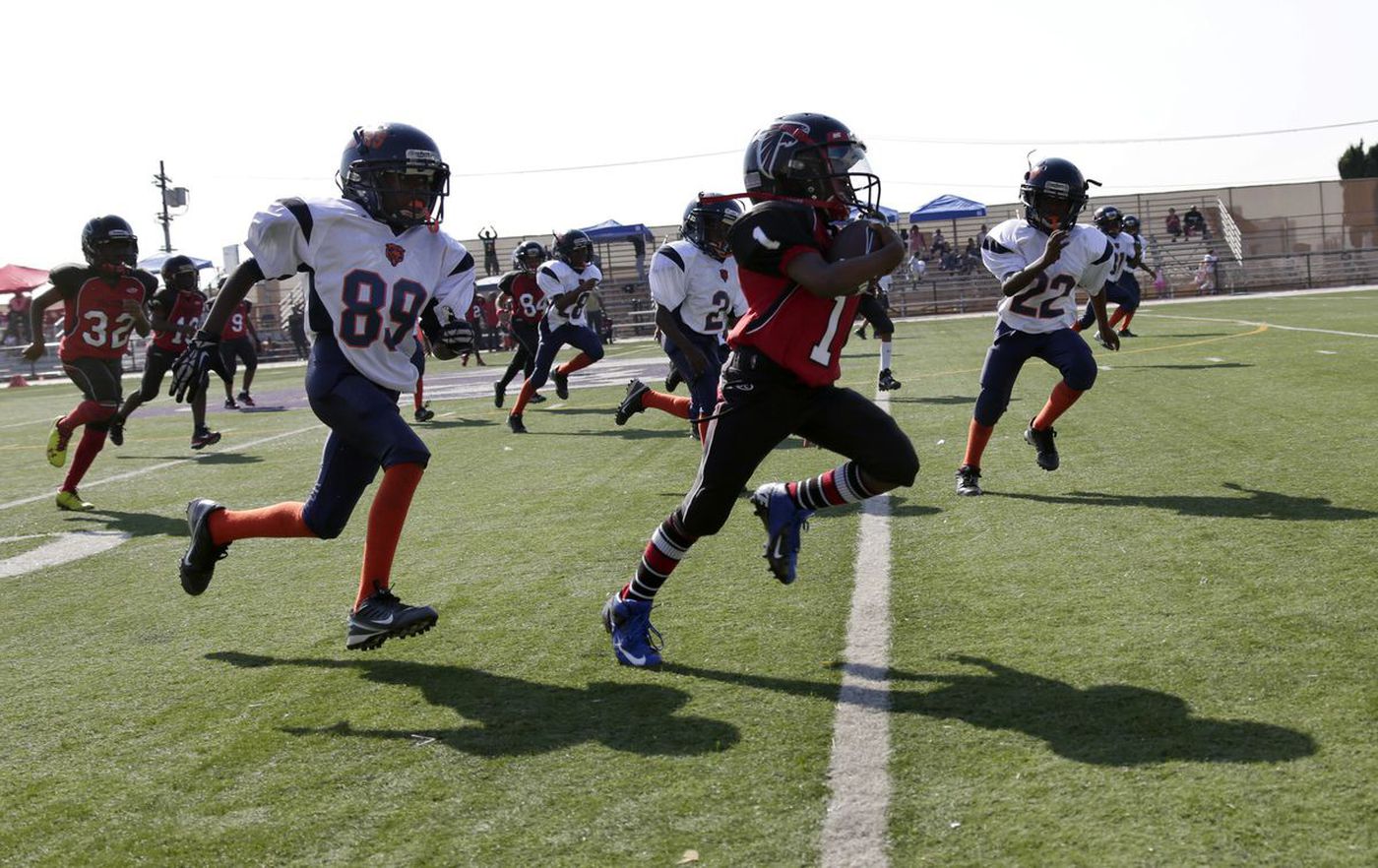 The LAPD-coached youth football team Watts Bears (in white) pursue a member of the Southern California Falcons during a 2013 game. (Credit: Irfan Khan / Los Angeles Times)