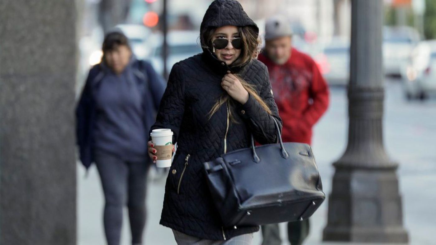 A woman clutches her coat close as she bundles up in colder than usual weather in the Los Angeles area amid frigid temperatures in an undated photo. (Irfan Khan / Los Angeles Times)