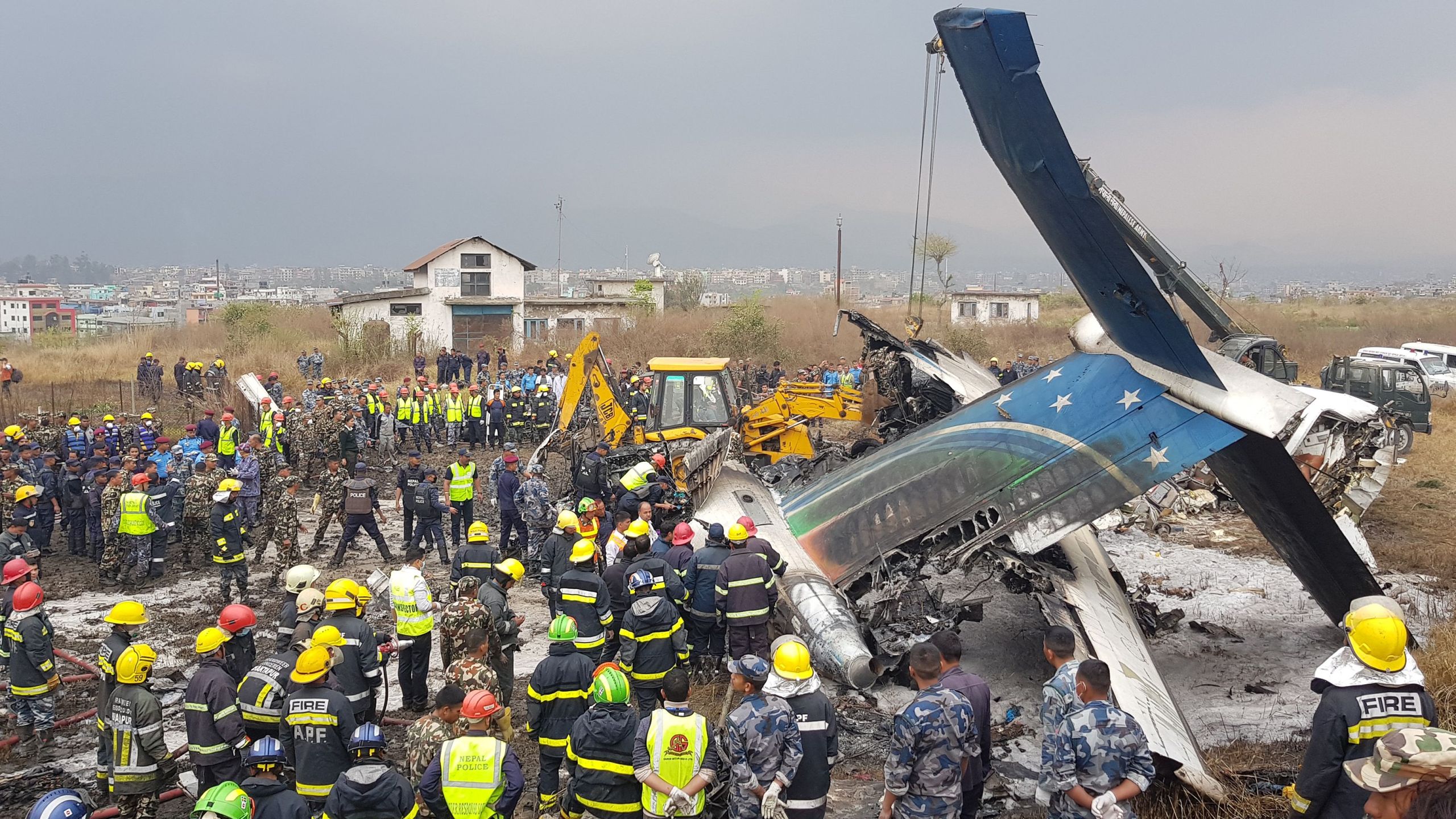 Nepali rescue workers gather around the debris of an airplane that crashed near the international airport in Kathmandu on March 12, 2018. (Credit: PRAKASH MATHEMA/AFP/Getty Images)